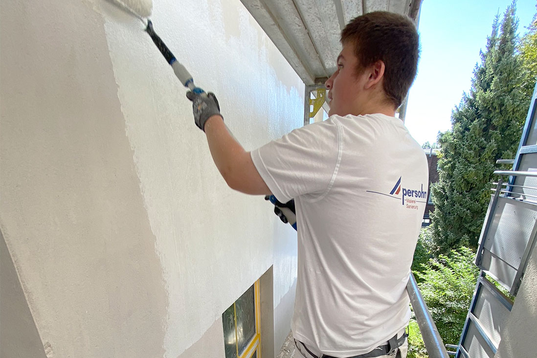 Azubi beim streichen einer Hauswand